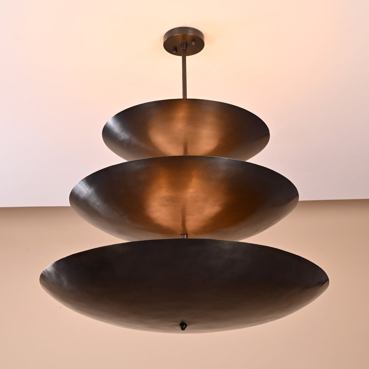 Angled view of triple bowl chandelier in blackened brass, handcrafted modern ceiling fixture