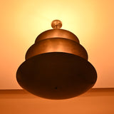 Blackened brass chandelier illuminated from below, creating warm ambient upward lighting