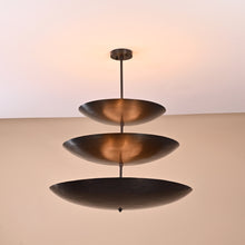 Three-layer brass chandelier in blackened finish viewed from side, minimalist industrial ceiling light