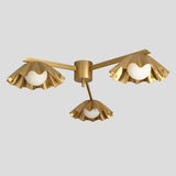 Brass flushmount chandelier with three decorative ruffled shades, highlighting white glass globes for modern and stylish interiors.
