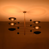 Turin Disc Balance Chandelier installed on ceiling with six black disc shades and warm ambient glow.