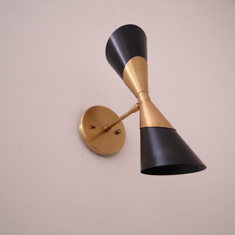 Upward tilted view of brass and black double cone wall sconce highlighting the flared cone shades and brass center.