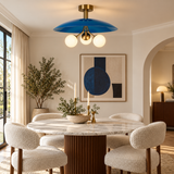 Valencia 3 light blue sculptural disc chandelier with brass-tone arms and illuminated opal globes above a modern dining table.