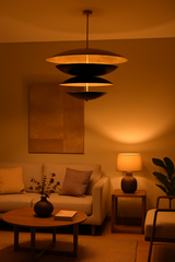 Modern tiered black and gold chandelier casting a warm ambient glow in a cozy living room setting, perfect for contemporary and minimalist interiors