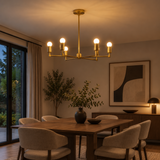 Venice 6 light brass-tone chandelier illuminated above a dining table in a warm contemporary dining room.