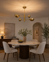Venice 2 light brass orb and bowl chandelier installed above a round dining table in a warm modern dining room.