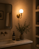 Verona Modern Globe Glass Wall Sconce installed above a bathroom vanity, providing warm ambient lighting in a contemporary luxury interior.