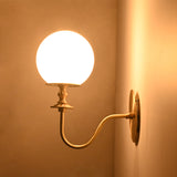 Side view of the illuminated Verona Modern Globe Glass Wall Sconce emphasizing the graceful curved arm and softly glowing opal globe.