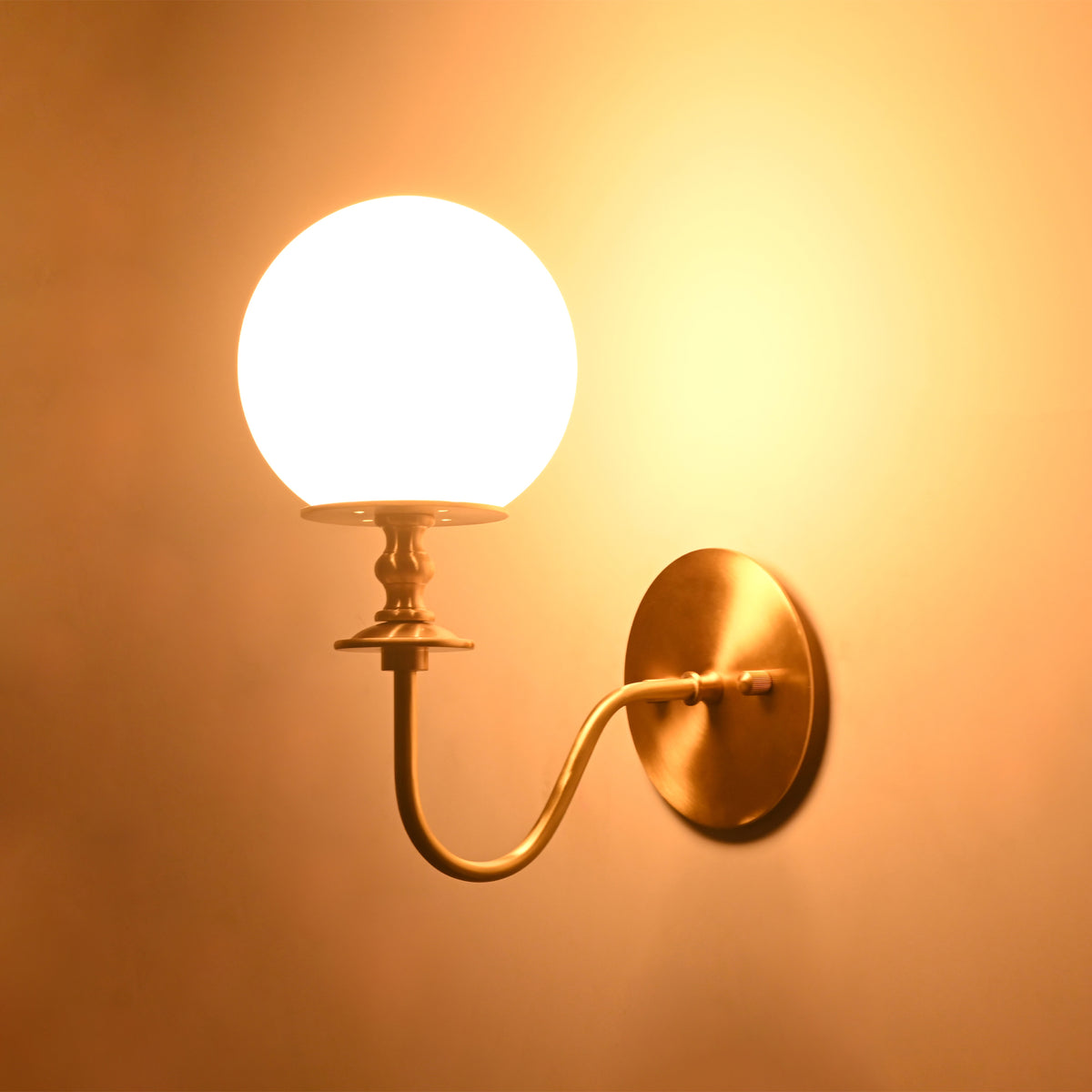Angled close-up of the illuminated Verona Modern Globe Glass Wall Sconce showcasing its elegant curved arm and warm ambient lighting.