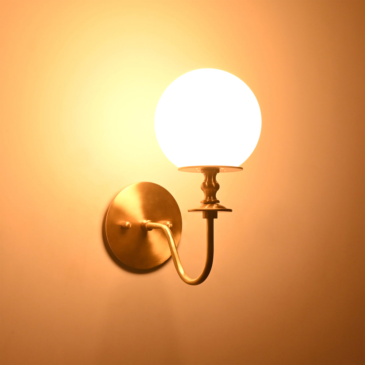 Verona Modern Globe Glass Wall Sconce casting a soft warm ambient glow against the wall, highlighting its frosted globe shade.