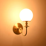 Verona Modern Globe Glass Wall Sconce casting a soft warm ambient glow against the wall, highlighting its frosted globe shade.