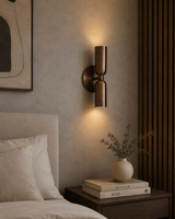 erona double cylinder wall sconce installed beside a bed with warm up and down lighting in a modern bedroom, Model 32833.