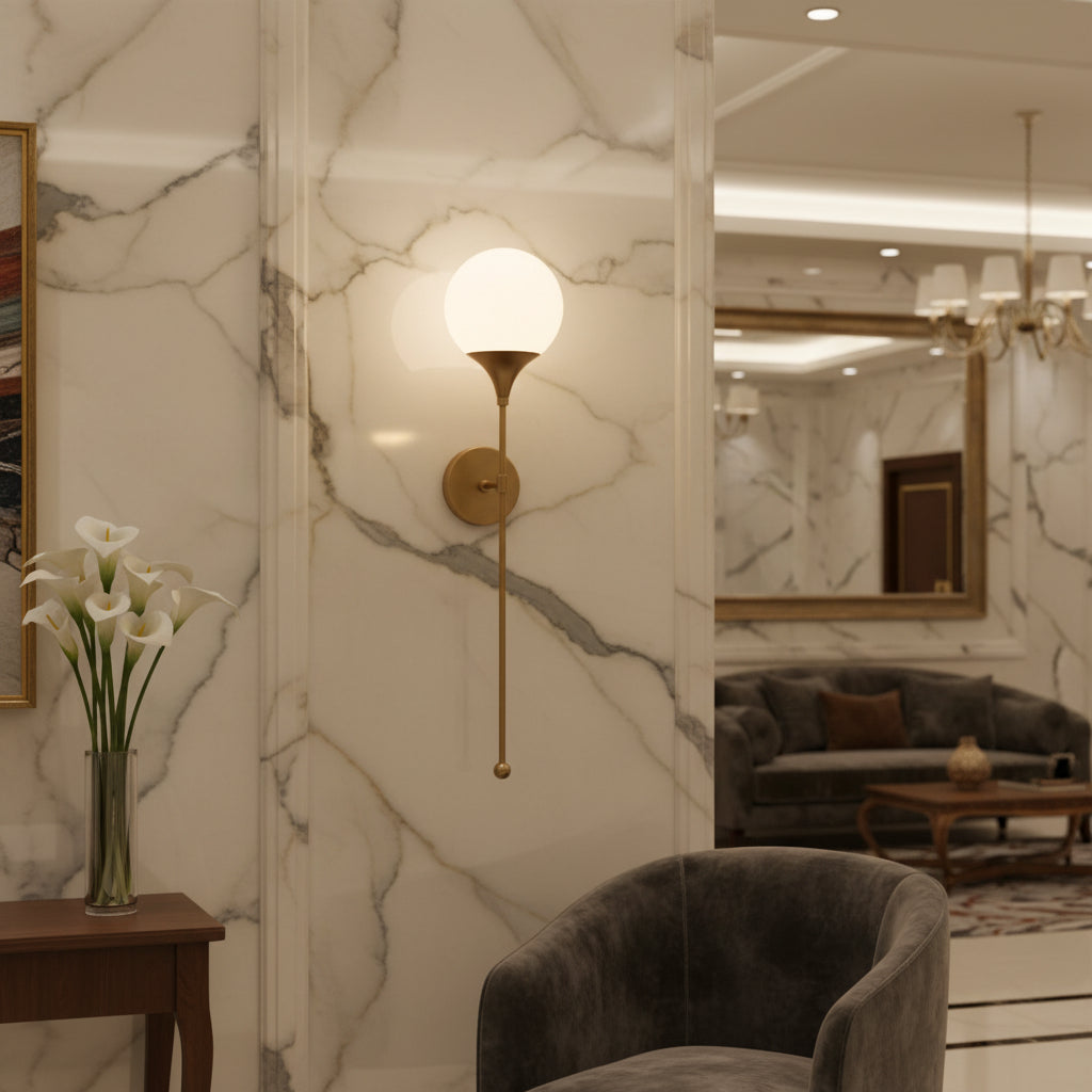 A modern wall-mounted sconce with a spherical frosted glass globe shade and a slim brass-finished metal arm and wall mount, shown against a plain white background.