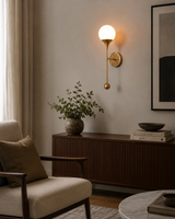 Verona Globe Glass Wall Sconce installed in a modern living room, providing warm ambient lighting above a wooden console cabinet.