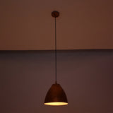 Verona hammered copper bell pendant light suspended in a dark setting with warm focused downward illumination and a handcrafted hammered copper shade.