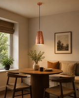 Verona hammered copper cylinder pendant light installed above a round dining table, providing warm ambient illumination in a modern Scandinavian dining room.