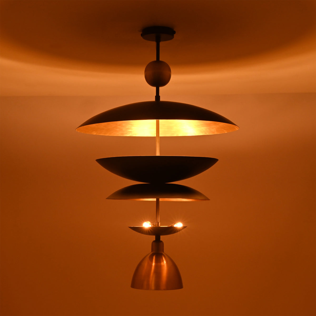 Night view of the Verona Layered Disc Pendant Chandelier with layered metal shades producing a warm, inviting ambient glow.