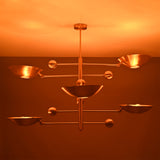 Verona Orbital chandelier shown illuminated, casting warm light through sculptural bowl shades and offset arms.