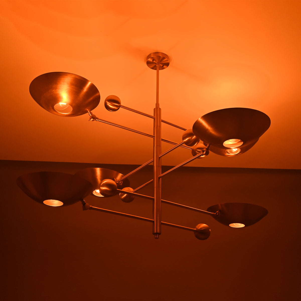 Verona Orbital chandelier shown illuminated from an angled view, highlighting layered bowl shades and warm glow.