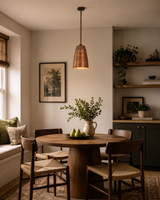 Verona ribbed bell pendant light installed above a round dining table in a modern dining room, showcasing its handcrafted ribbed copper shade and warm ambient lighting.