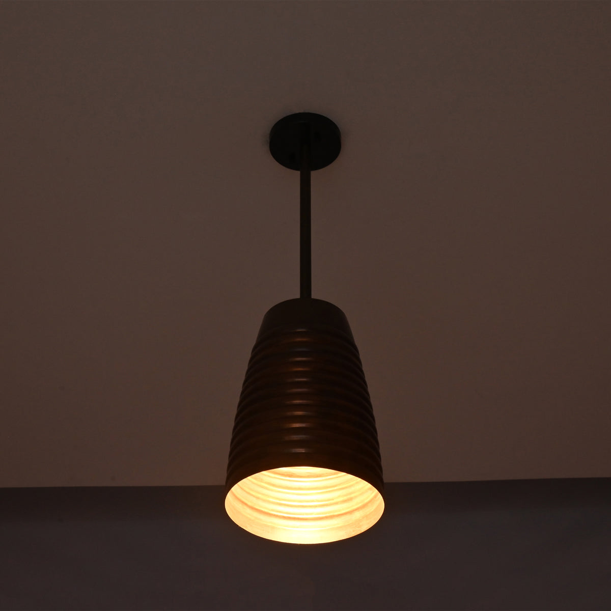 Close-up night view of the Verona ribbed bell pendant light highlighting its warm downward glow and handcrafted ribbed copper shade.
