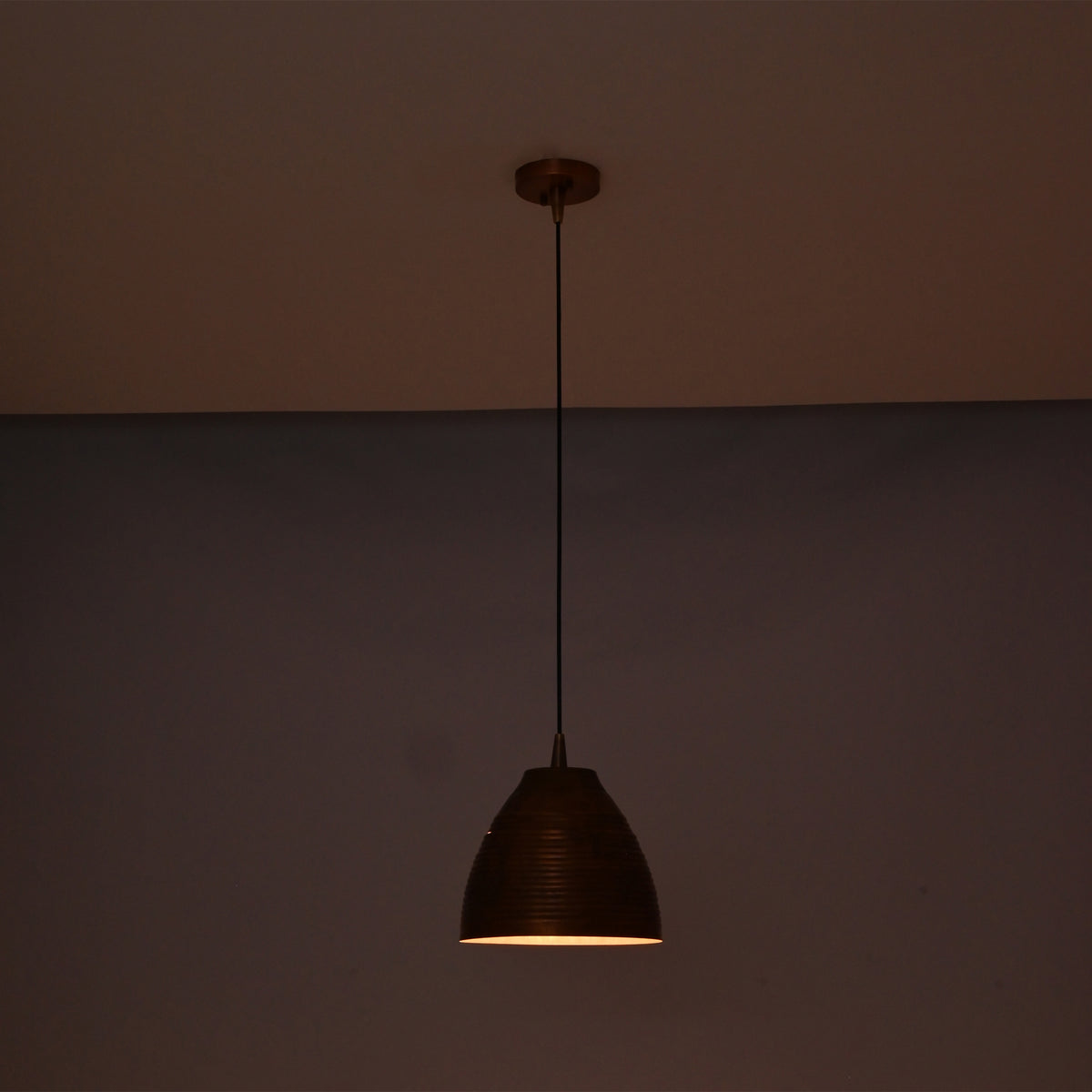Verona ribbed copper dome pendant light illuminated with a warm ambient glow, highlighting the handcrafted ribbed copper finish.
