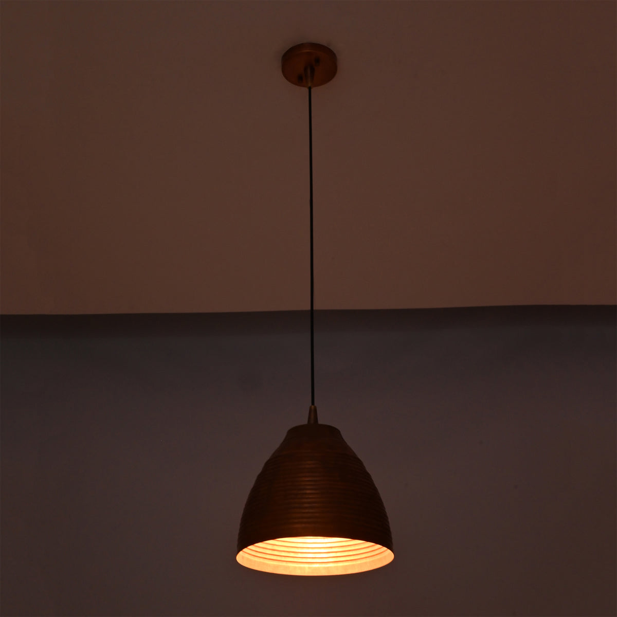 Close-up lit view of Verona ribbed copper dome pendant light emphasizing the textured interior and warm focused illumination.