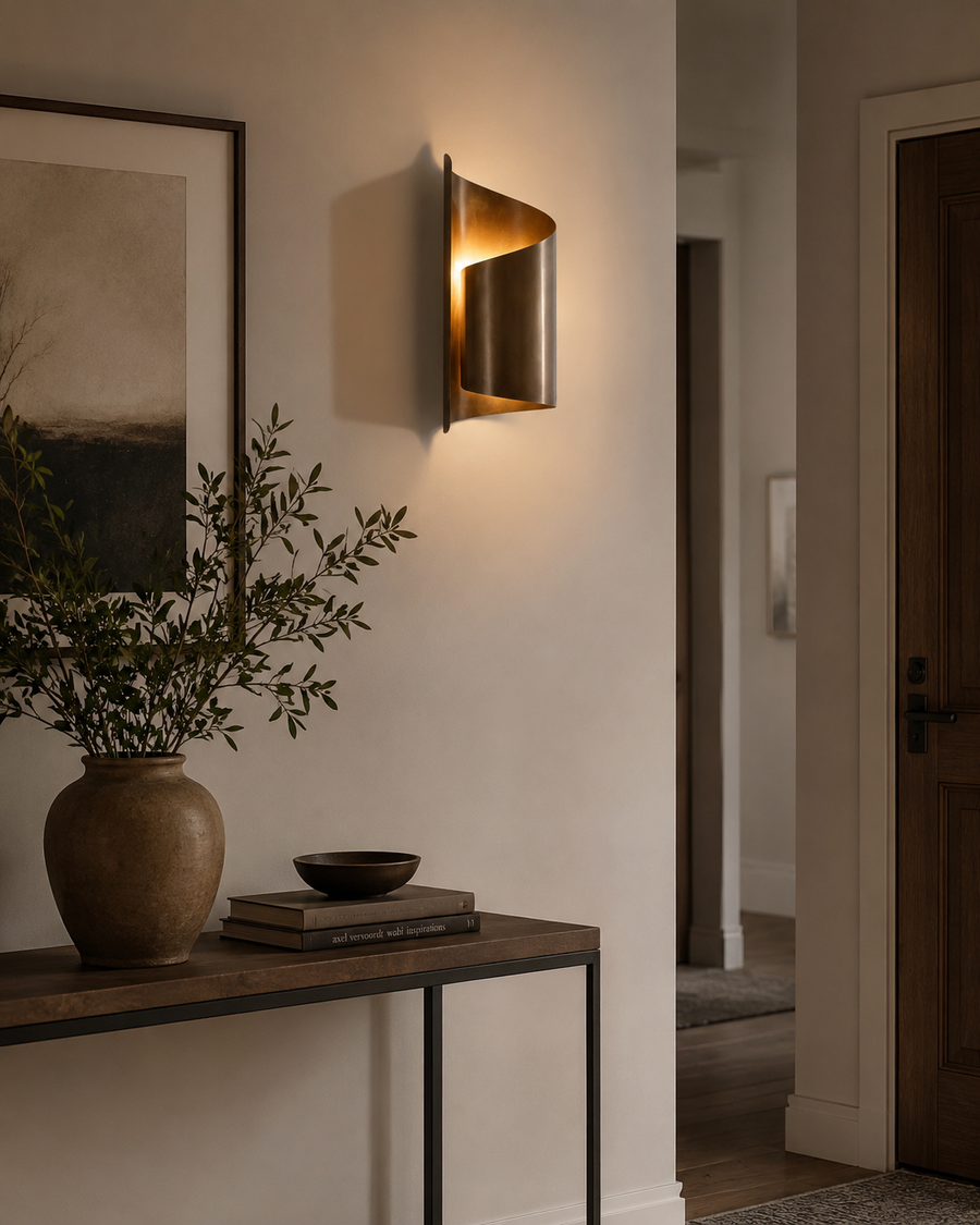 Verona sculptural curved metal wall sconce with warm ambient lighting styled in a modern entryway interior
