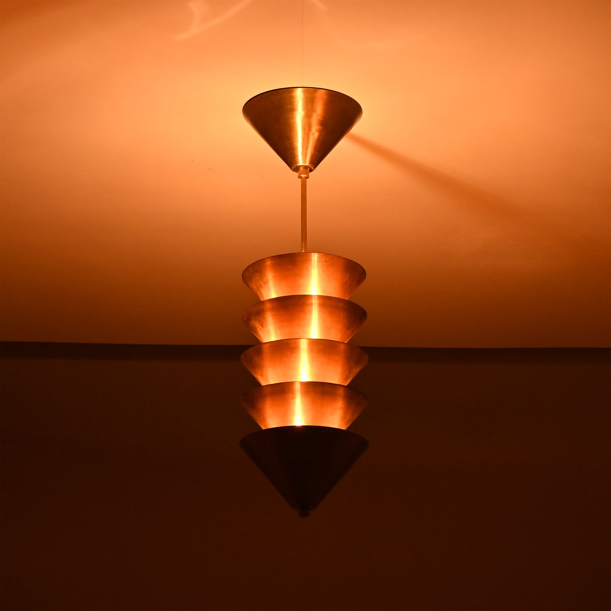 Verona Stacked Cone Pendant close illuminated view with warm ambient light and stacked shade silhouette.