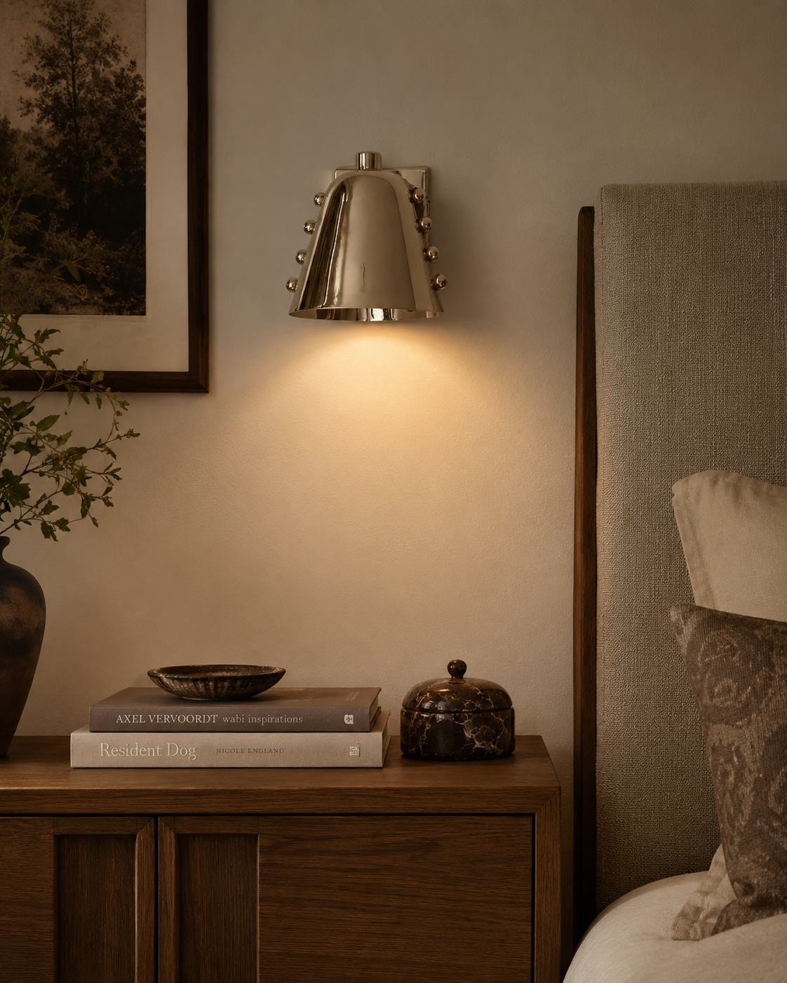 Verona Studded Cone Wall Sconce installed beside a bed in a modern bedroom, casting warm ambient downward light with an elegant polished metal finish.