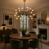Versailles 36 light black and brass Sputnik chandelier illuminated above a round dining table in an elegant Mid-Century Modern dining room.