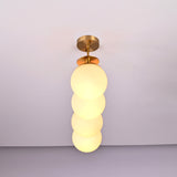 Handmade brass pendant light with four stacked frosted globes in vertical alignment, modern chandelier for hallways and entryways.