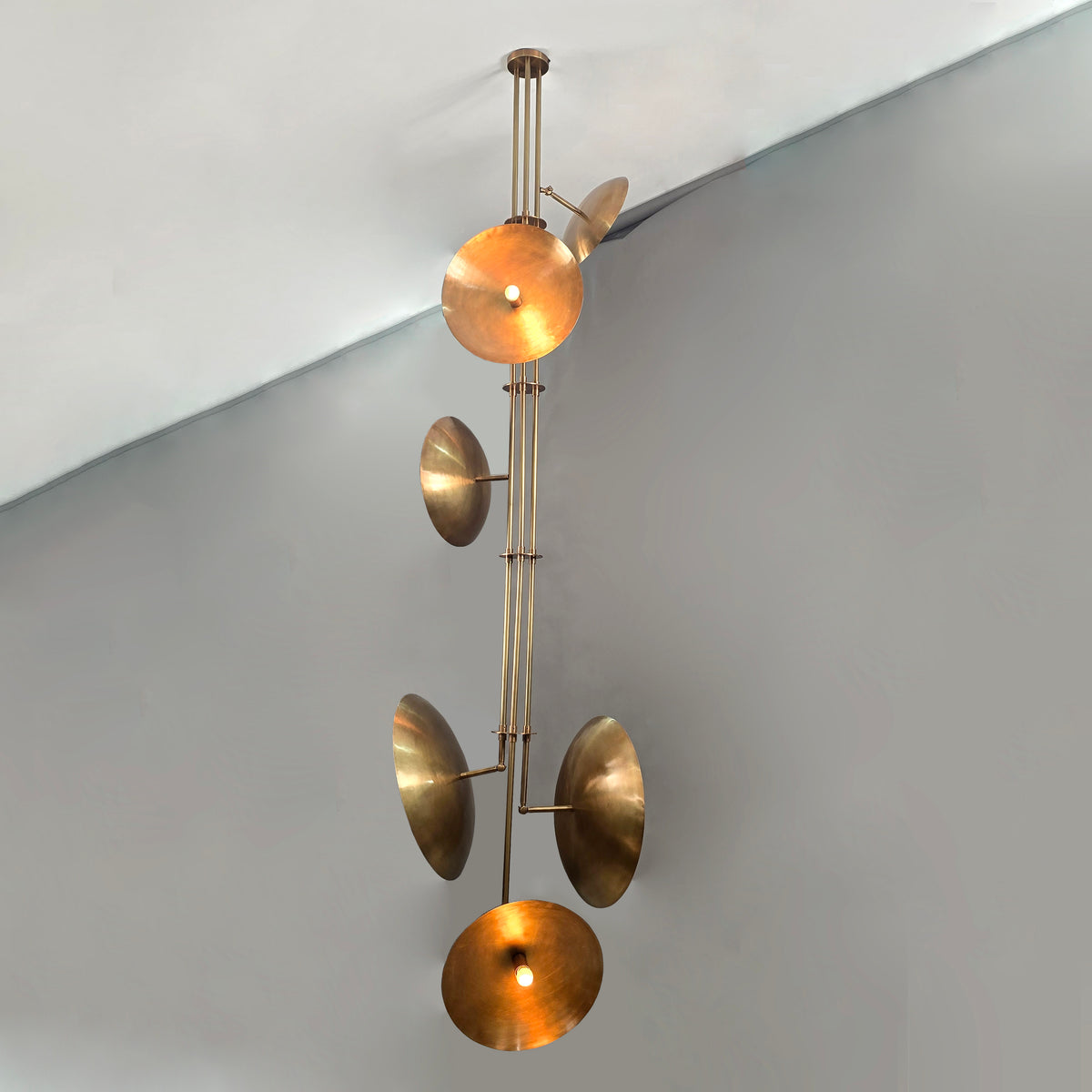 Luxury vertical brass chandelier highlighting brushed metal texture and balanced disc arrangement.
