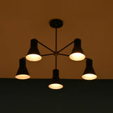 Five-light black chandelier glowing softly in a dim room, creating a cozy atmosphere.