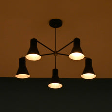 Five-light black chandelier glowing softly in a dim room, creating a cozy atmosphere.