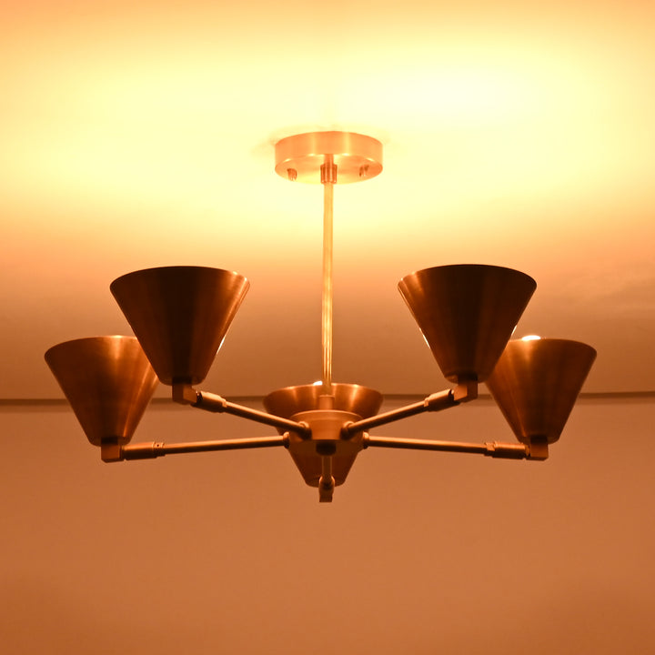 Brass cone chandelier illuminated with warm amber light, creating a cozy and inviting atmosphere in contemporary interiors.