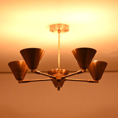 Brass cone chandelier illuminated with warm amber light, creating a cozy and inviting atmosphere in contemporary interiors.