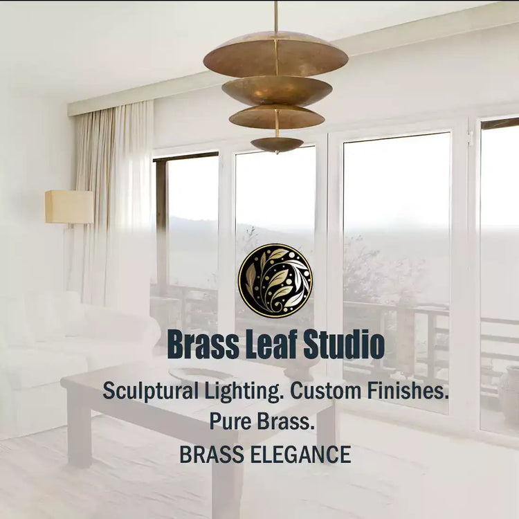 A modern living room showcasing sculptural brass lighting from Brass Leaf Studio, with a large tiered pendant light and a glowing wall sconce.