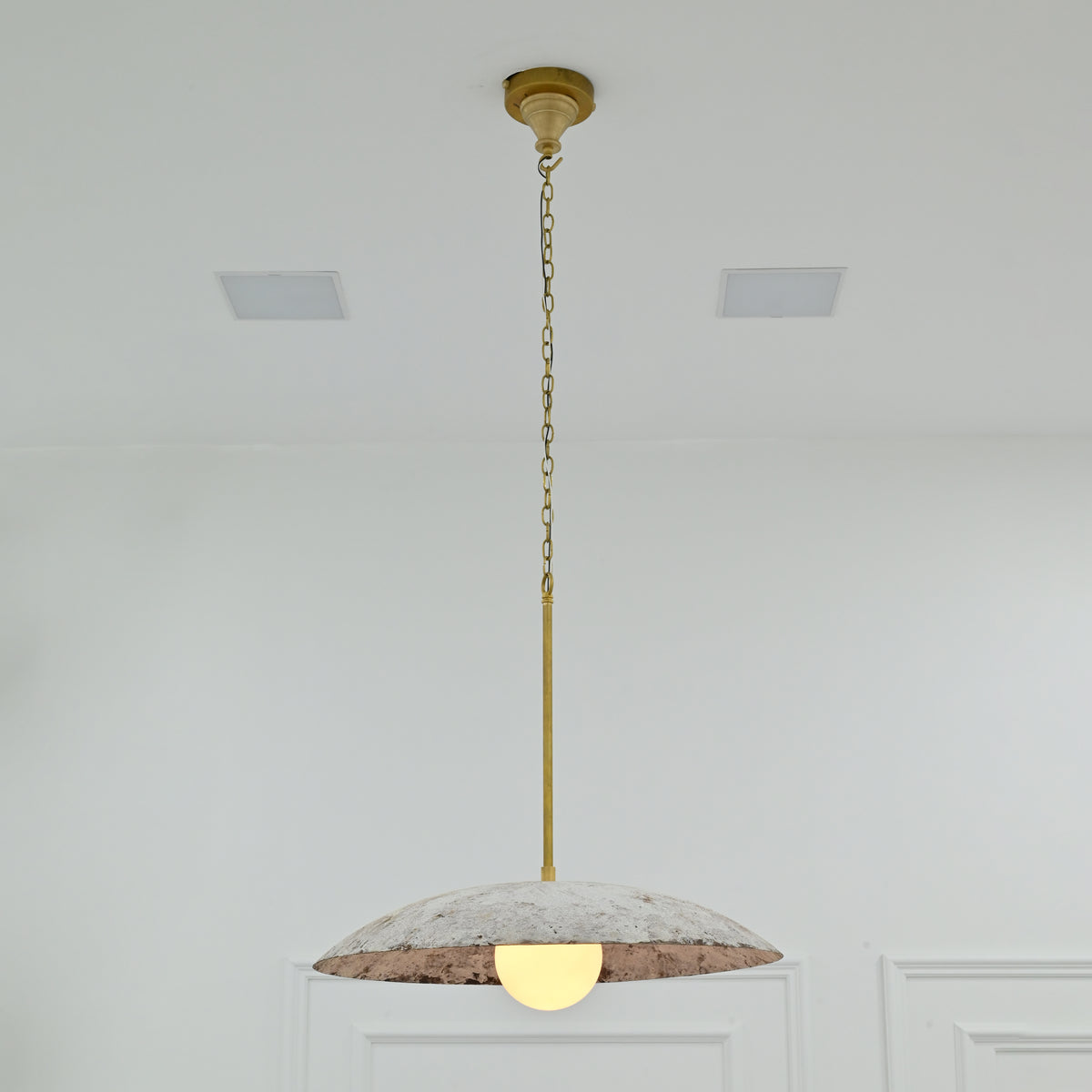 Front view of Wellington 24-inch textured dome pendant light with weathered white metal shade, antique brass suspension and glowing globe bulb.