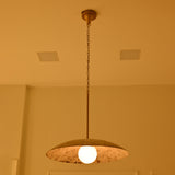 Wellington rustic dome pendant light illuminated in warm ambient lighting, highlighting the distressed white shade, brass chain and softly glowing bulb.