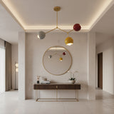 Zurich 3 light colorful globe chandelier illuminated to highlight its brass frame and sculptural Mid-Century Modern design.