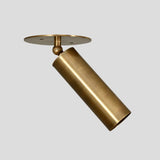 Adjustable brass cylinder spotlight with ceiling mount, handmade industrial minimalist design, side angle view.