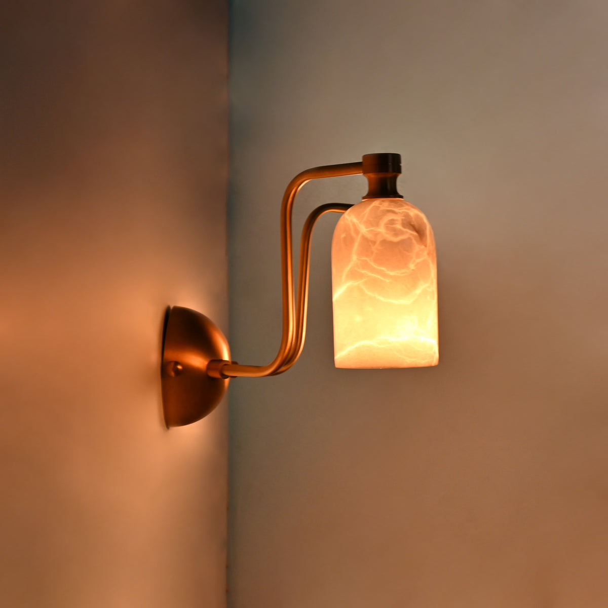 Alabaster shade brass wall fixture with rounded canopy, curved arms, and warm diffused illumination