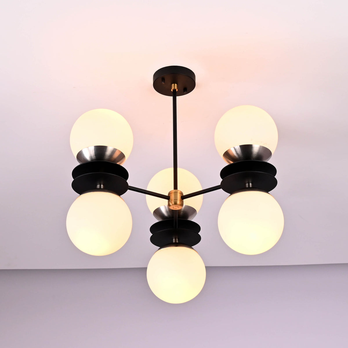 Side angle of modern brass and black chandelier with six round opal glass globes