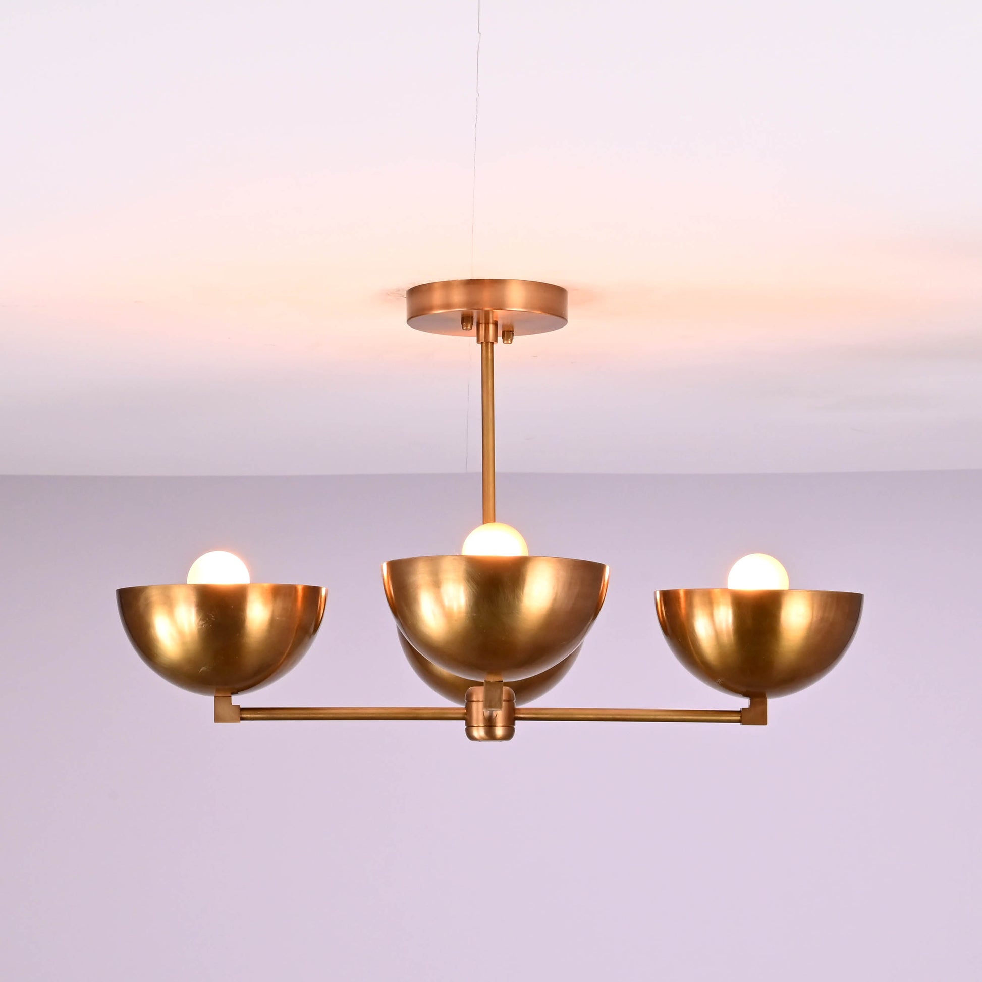 Side angle of modern brass chandelier with four bowl shades and E26 bulb sockets