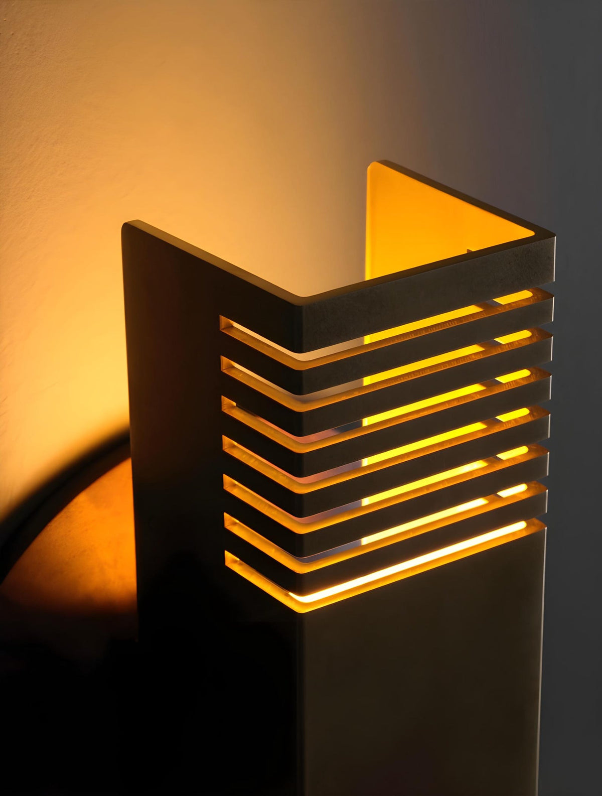Architectural brass wall sconce viewed from top angle showcasing layered slotted design and indirect light diffusion