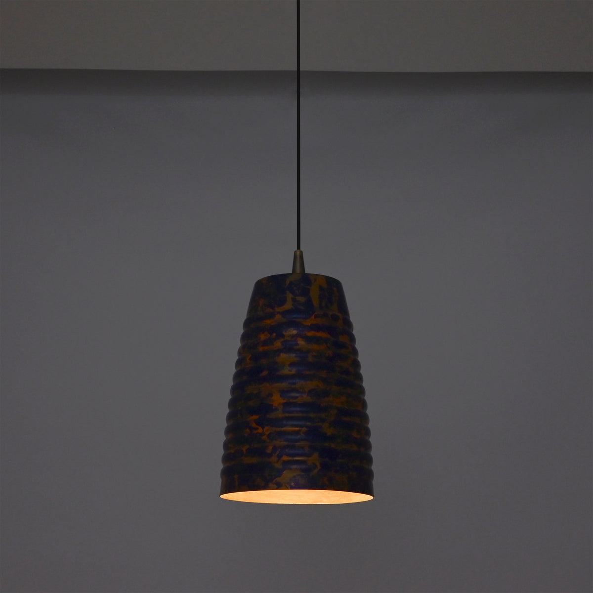 Artistic ribbed pendant light adding warm ambient glow to a stylish interior with wooden furniture and soft décor