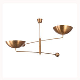 Asymmetrical brass ceiling chandelier with sculptural arms, bowl shades, and warm reflected ceiling light