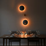 Asymmetrical brass wall sconce design with two circular blue shades and warm decorative wall lighting effect