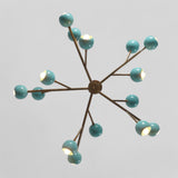 Bottom view of atomic-style brass chandelier showing symmetrical brass arms and aqua blue globe lights.